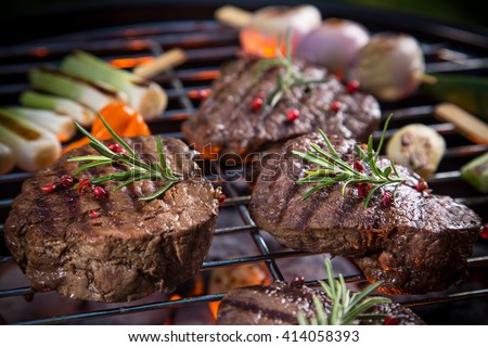 Assorted delicious beef steaks with vegetable on a barbecue grill.