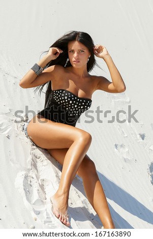 Beautiful girl with perfect figure in a bathing suit background  on white sand