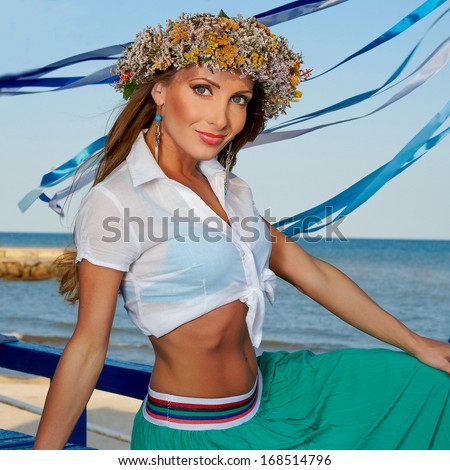 girl with a wreath and blue ribbons  on a background of the sea