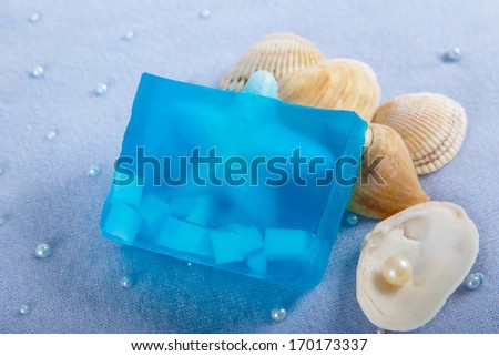 Natural skincare products of  exfoliating scrub, soap and sea shells on a blue background