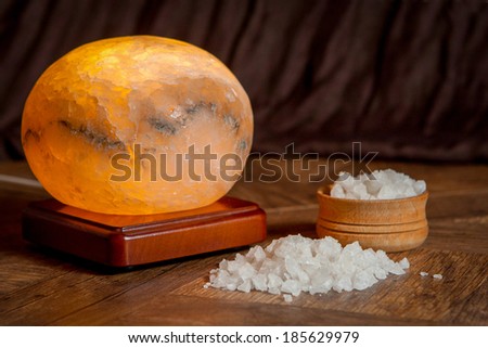 Healthy sea salt and salt lamp on wooden bowl closeup