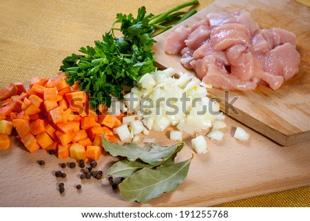 raw chicken meat on cutting board with vegetables and spices