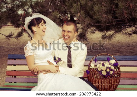 funny bride and groom sit on the bench laughing and having fun