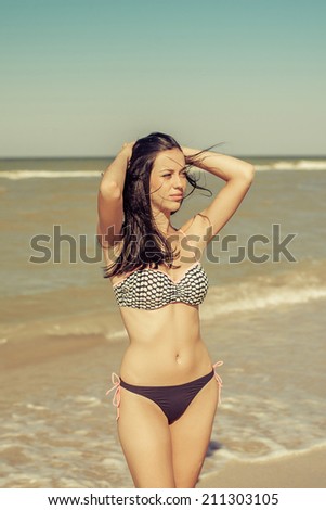 young beautiful woman brunette in bikini on sea background