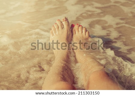 caucasian  girl beautiful  legs in sea with red nail polish on the nails