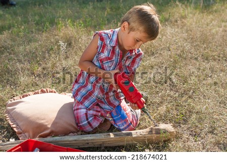 Little boy with toy hand tools drill. Emotional, hard at work outside.