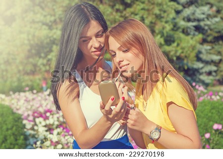young Girls Applying Make up and Looking in the Mirror. Pretty Teens Having Fun and Putting Makeup Lipstick or Lip gloss. women Outdoors. Cosmetics