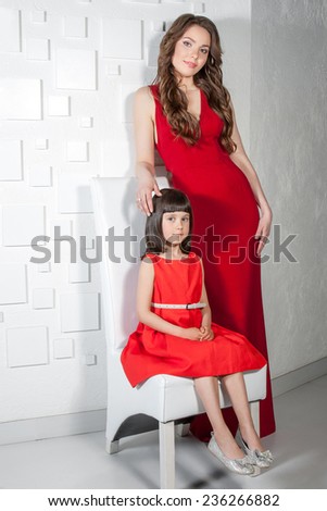 Happy family. Beautiful mother and daughter sitting in a red dress. Positive human emotions, feelings, emotions.