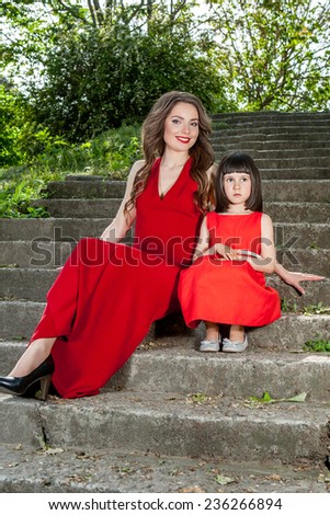 Happy family. Beautiful mother and daughter sitting in a red dress. Positive human emotions, feelings, emotions.
