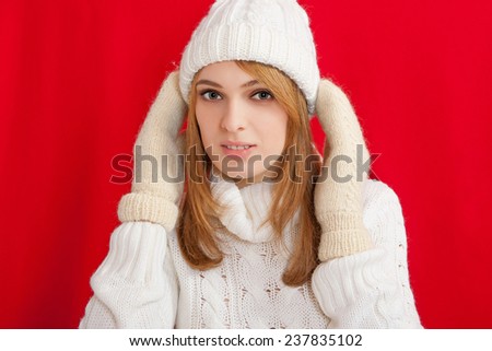 Beauty Girl wearing fashion white knitted hats and mittens. Winter cold  holiday. Woman in red background portrait.