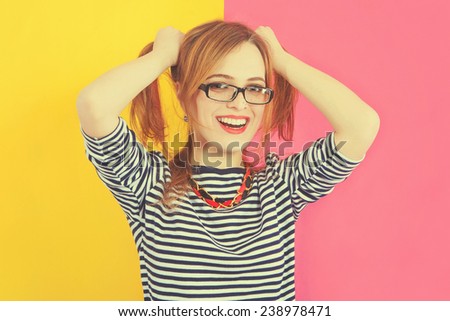 Fashion stunning closeup portrait of pretty attractive nice girl with red lips, freckles and glasses posing on pink-yellow vivid color  background