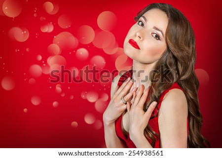Sexy woman in red dress with long hair. Sensual pose, looking at  camera. With red lipstick on her lips.
