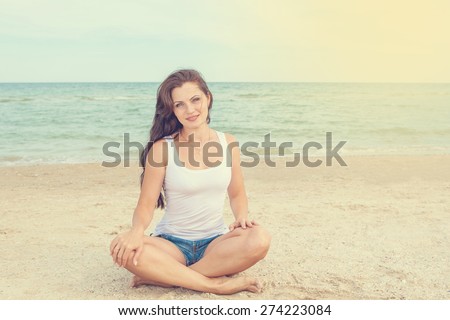 pretty beautiful sport fashion woman in white T-shirt posing in summer near the sea and blue sky in sunshine with gorgeous smile in happy mood on tropic island on vacation