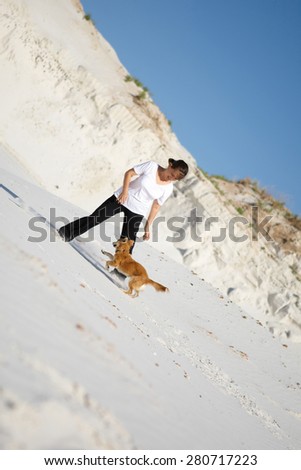 young woman playing with her red dog on white sand. laughing, having fun