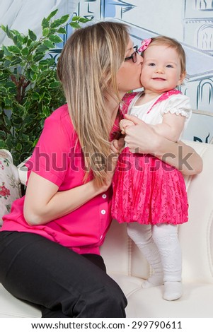 Happy mother with  baby daughter in a beautiful dress at home. Happy smiling. Mother kissing her daughter