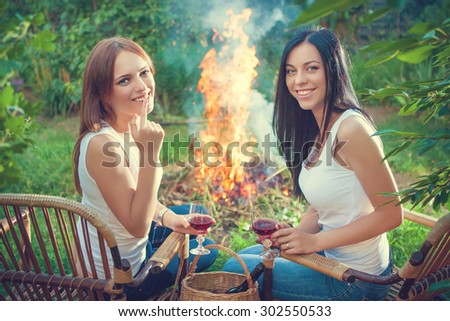 summer holidays and vacation - girls with red wine glasses near bonfire
