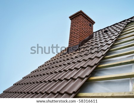 Roof under constructions with lots of tile and red brick chimney