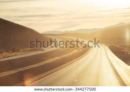 Highway at sunset leading from the Valley of Fire State Park in Las Vegas at the state Nevada. The picture have the car what moving on the highway.
