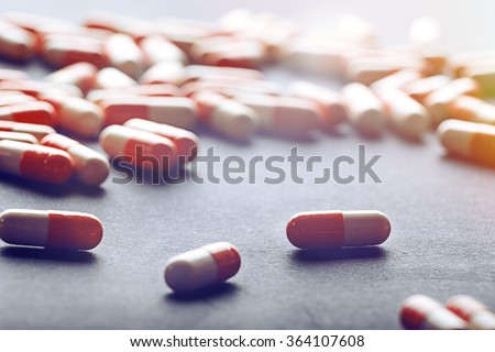 Drug prescription for treatment medication. Pharmaceutical medicament, cure in container for health. Pharmacy theme, Heap of red orange white round capsule pills with medicine antibiotic in packages.