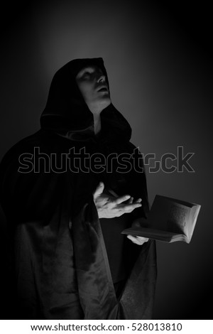 Portrait of a brutal man in a black robe with a book in their hands