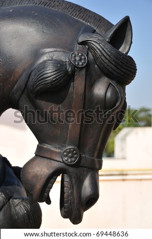 A black metal horse statue in front of the temple