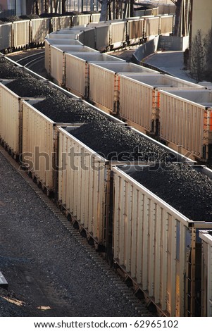 Boxcars filled with black coal on a long train. Power and energy production that contributes to global warming.