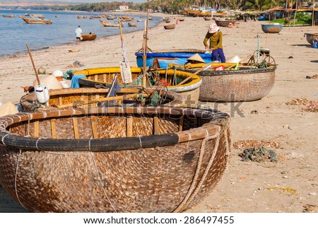 Fishing village, market and colorful traditional fishing boats near Mui Ne, Binh Thuan, Vietnam. Early morning, fishermen float to the coast with a catch.