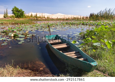 The boat lies on the bank of the lake of lotuses at White Sand Dunes - bau sen, bau trang, it\'s one of best destinations near Mui Ne, Binh Thuan. Vietnam.