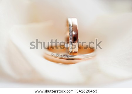 Golden wedding rings with diamonds lie on silk fabric. Symbol of love and marriage.