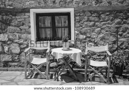 Table and two chairs outside an old stone house