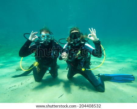 PALIOURI,GREECE-JULY 09 2014 :Two female scuba divers give the ok sign during a dive.Scuba diving is a growing sport all over the world
