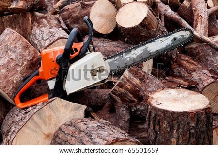 A chain saw sitting on a pile of logs