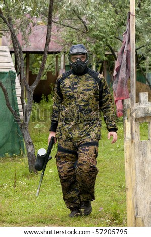 Camouflage dressed paintball player walking on the battle ground
