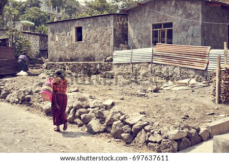 Poverty in Latin America / Poor Woman walking on dusty road in Mexico / Colorful latin clothing