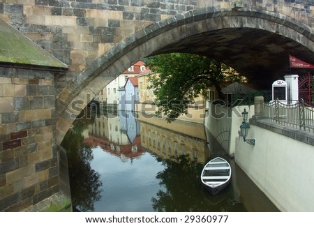 Small boat under the bridge on the Vltava river, Prague