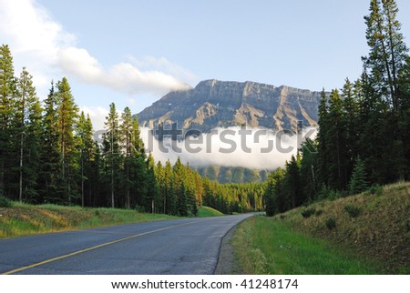 Summer view of road to mountains in sunset, banff national park, alberta, canada