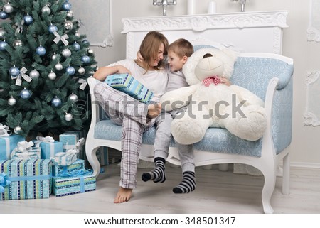 Funny mother and son in pajamas without a dad sitting with a gift near the Christmas tree. Toy instead Pope. Christmas Tree. Christmas scene. Christmas gifts. Christmas and New Year without a dad.