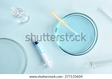 Chemical research in Petri dishes on blue background. Preparing plates in a microbiology laboratory. Inoculating plates. Vaccine ampoule. Top view. Natural light.