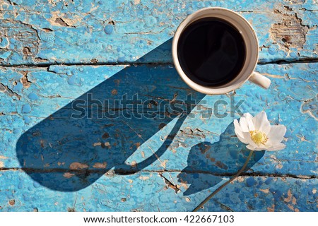 Coffee mug with flowers on blue rustic table from above, breakfast on Mothers day or Womens day, cup of black coffee, top view, vintage stile.