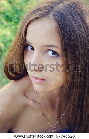 Beautiful thin girl with long hair and brown eyes is looking at you.