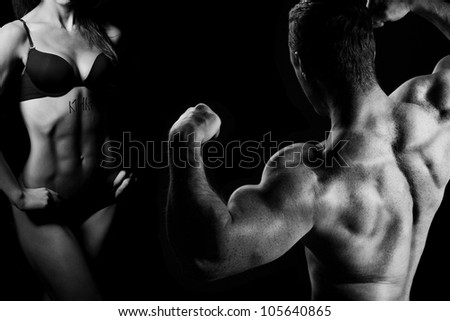Bodybuilding. Strong man and a woman posing on a black background - stock photo