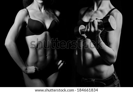 beautiful woman bodybuilder posing in black bikini on black background