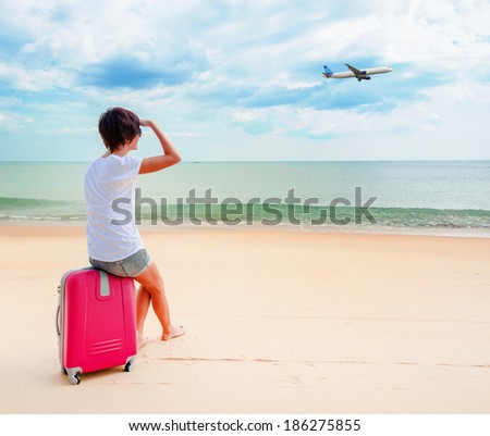Young woman with a suitcase on the beach