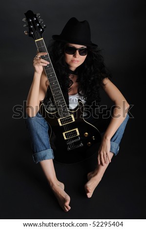 Girl in a hat and sunglasses sitting on the floor with a guitar in his hands