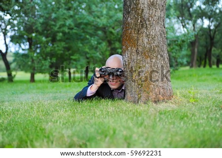 man in the green park looking through binoculars
