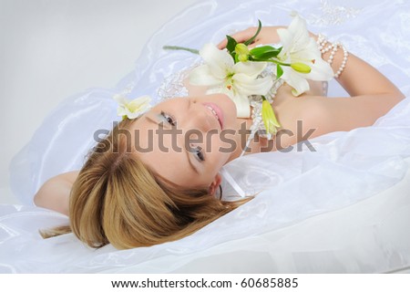 young bride with a bouquet of lilies on a gray background