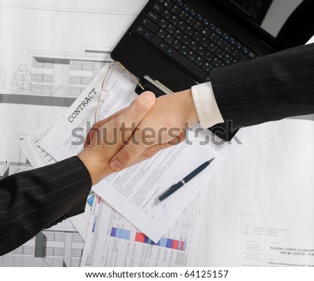 Handshake of two business partners after signing a contract. Focus on the documents