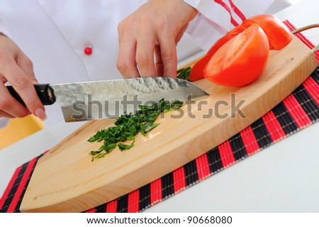 Chef in uniform cuts the tomato in the kitchen.