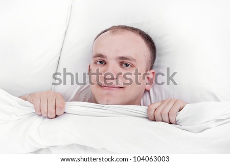 handsome young man in bed at home with a pleased and smiling face