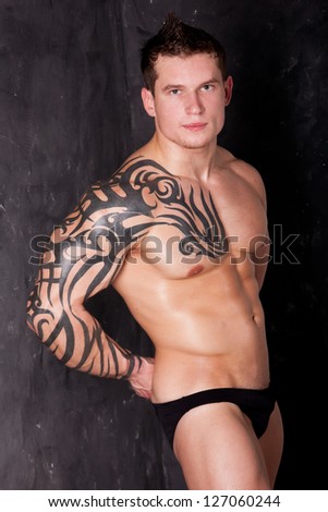 Studio shot of Muscular Sexy Man with tattoo on dark background